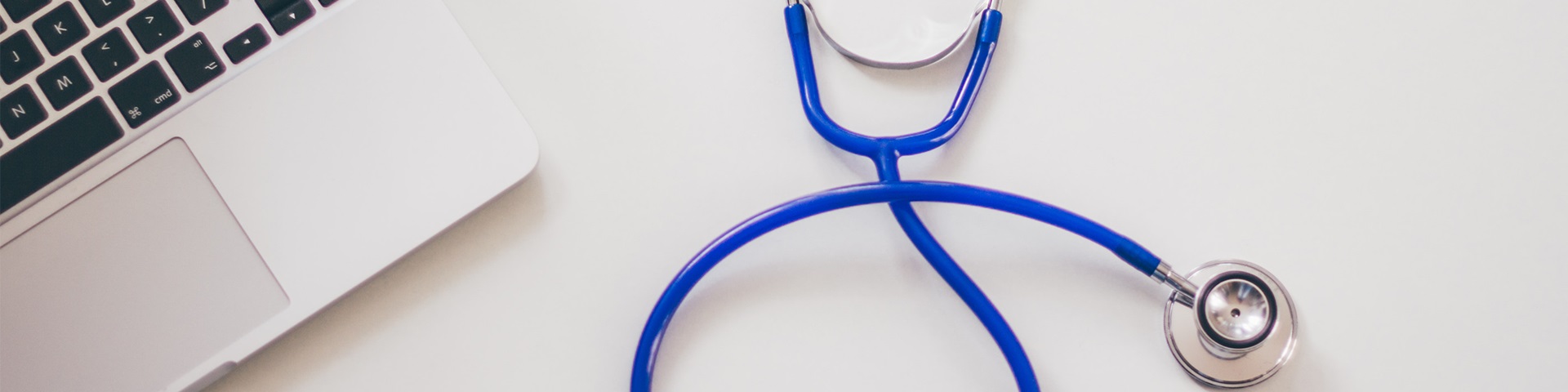 blue stethoscope and laptop on desk