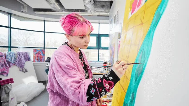 A student painting on a wall