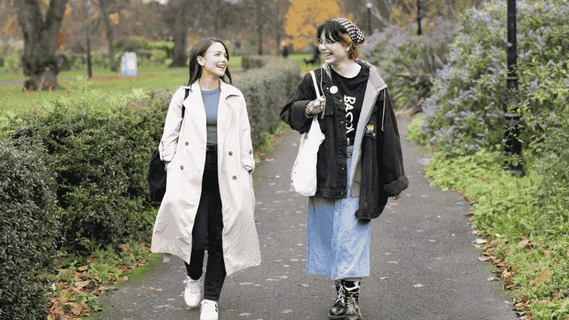 Two students walking through the park