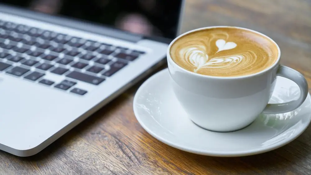 Cup of coffee and laptop on desk