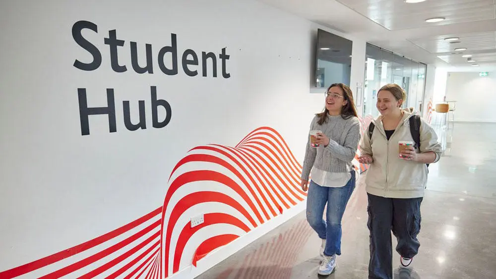 Two female students walking outside the student hub