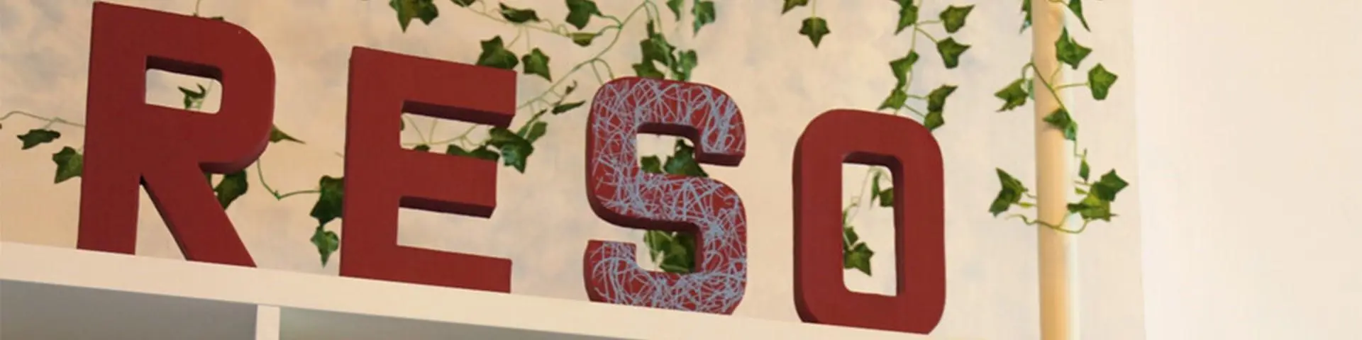 A red sign of Re So on top of shelving, with ivy in the background. 