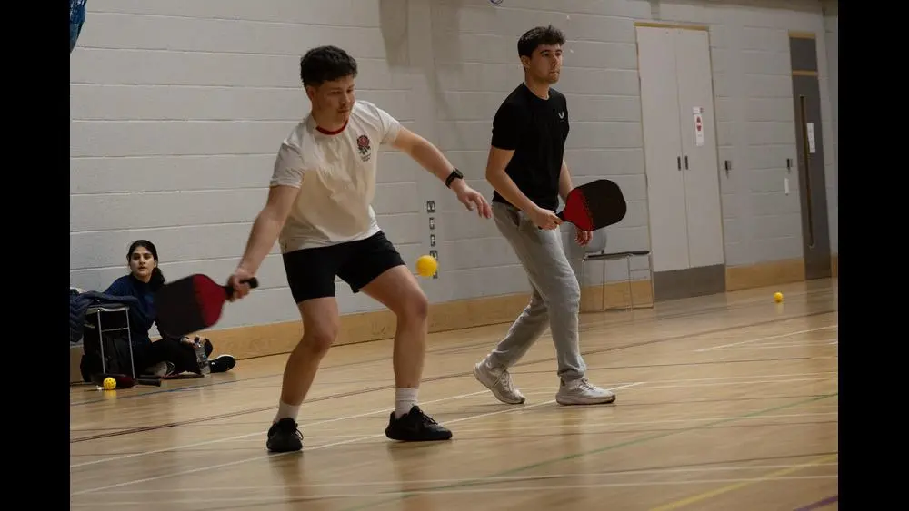 two students in the sports hall playing pickle ball