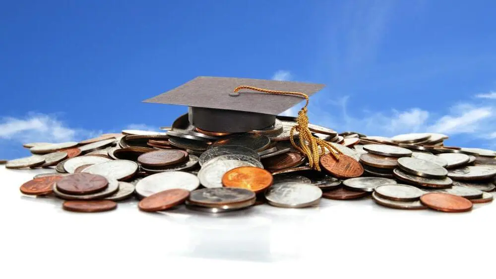 a mortar board hat sitting on top of a pile of coins