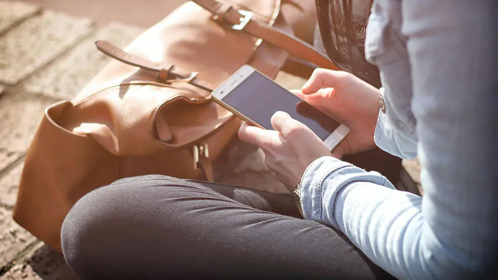 A person sat down on phone with bag