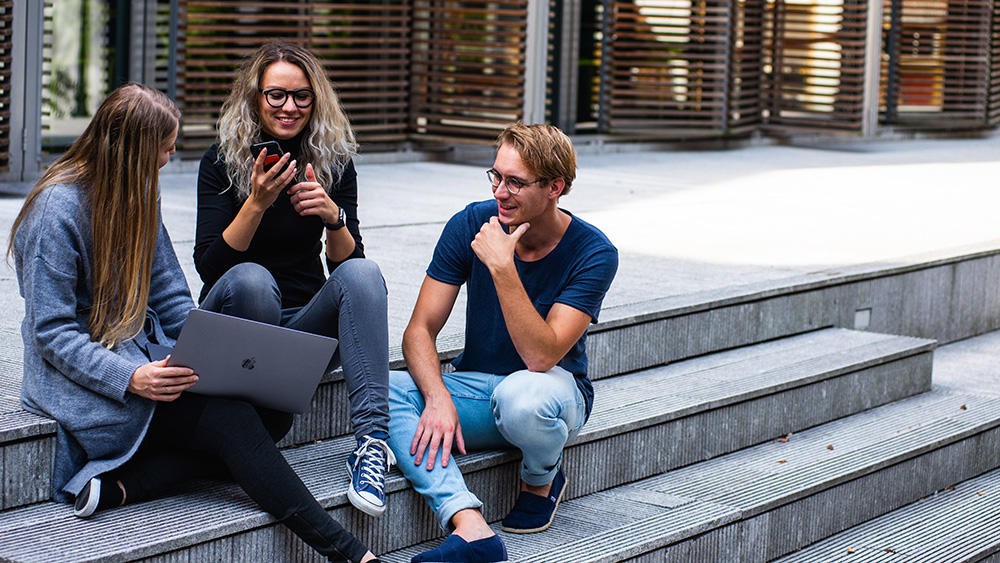 students sat on steps with laptop