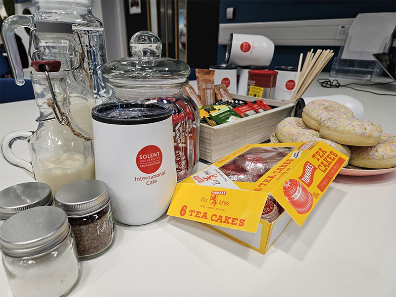 A collection of tea and coffee items, some cups and some Tunnock's tea cakes